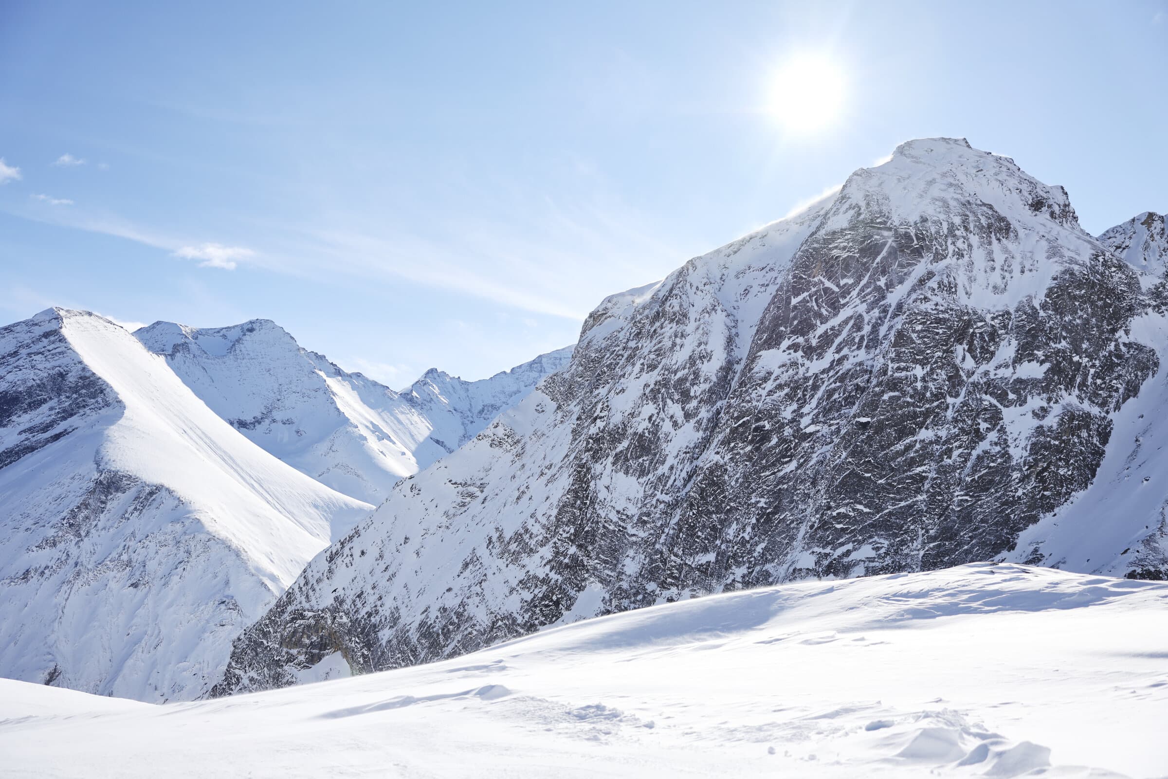 Snow-covered alpine peaks under bright sun